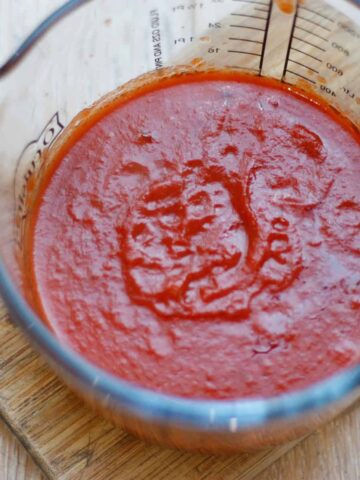 Tomato & Basil sauce in a glass jug on a wooden surface.