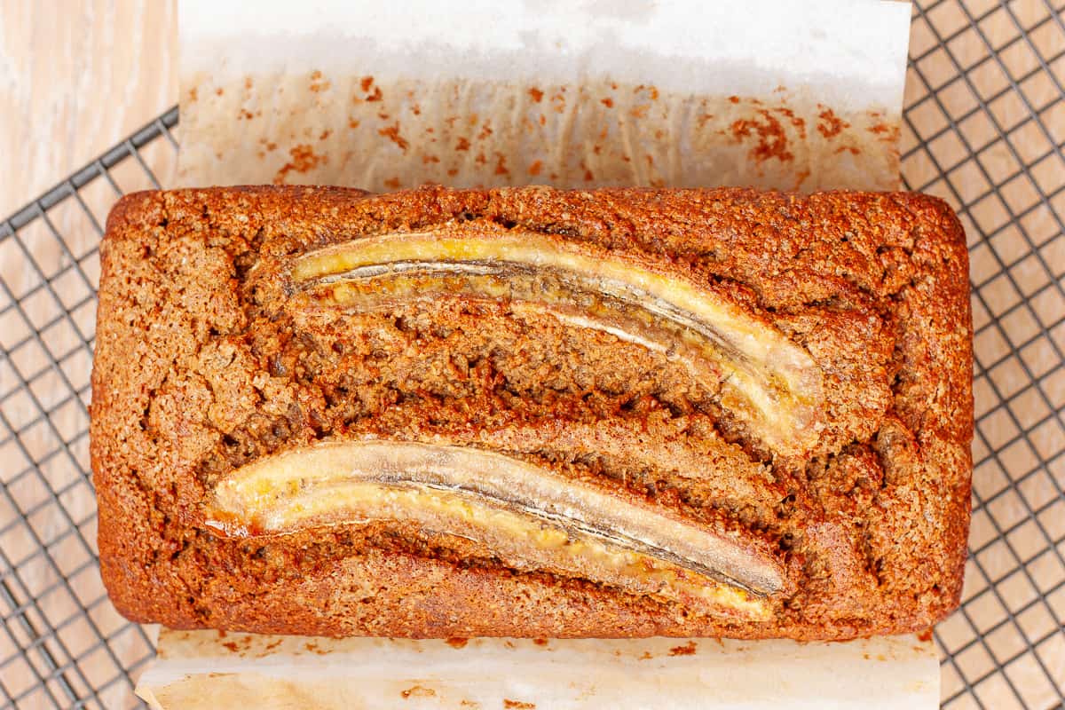 Whole baked banana cake, cooling on a rack.