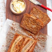 Slices cut from a banana cake loaf and smothered in butter.