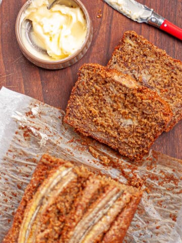 Slices cut from a banana cake loaf and smothered in butter.