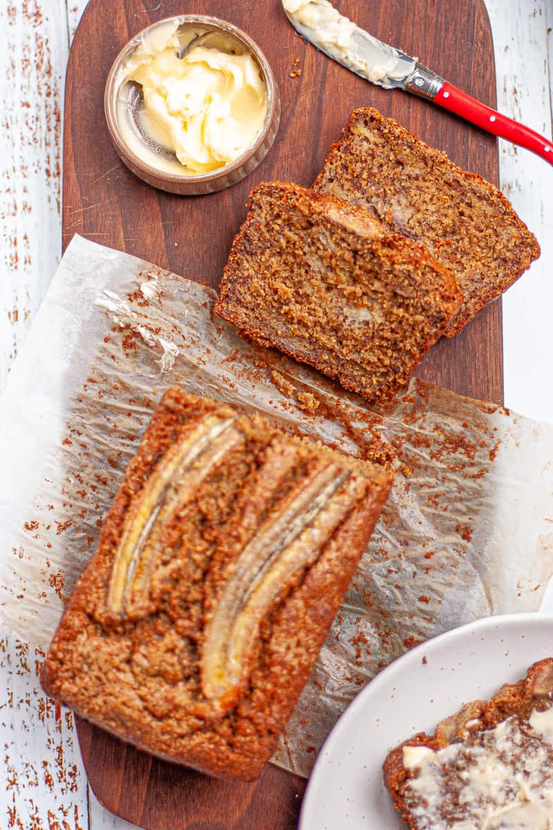 Slices cut from a banana cake loaf and smothered in butter.