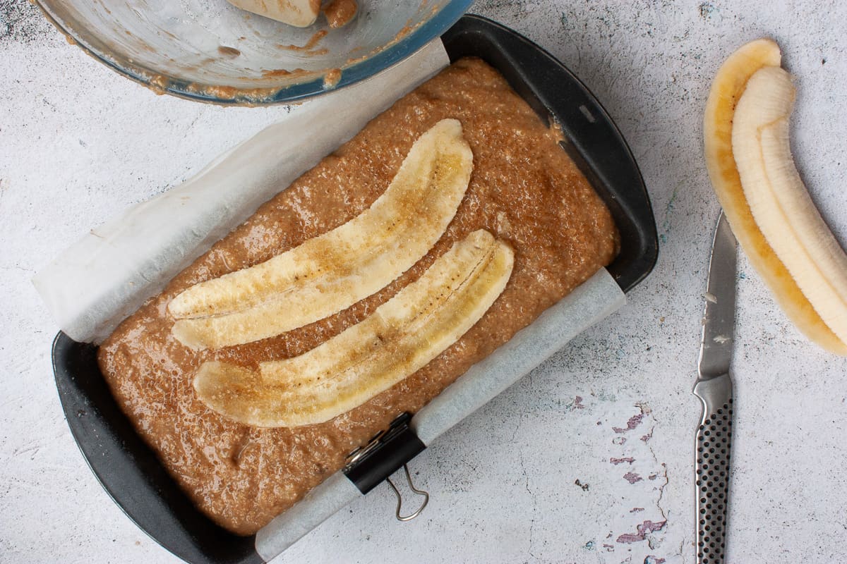 Banana cake ready to bake, with two long slices of banana on top.