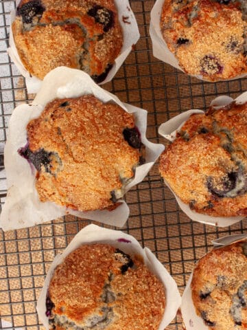 Sugar-crusted blueberry muffins cooling on a rack.