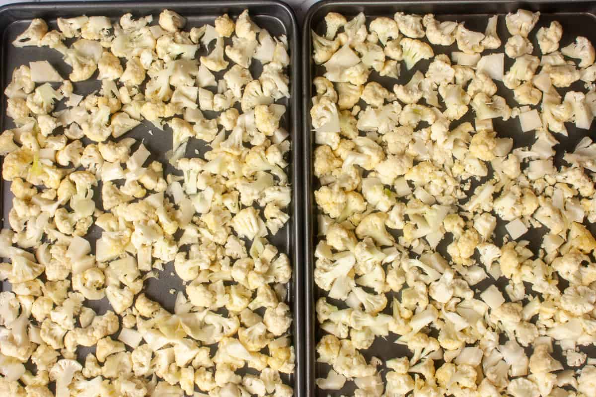 Cauliflower florets spread out in a single layer across two baking sheets.