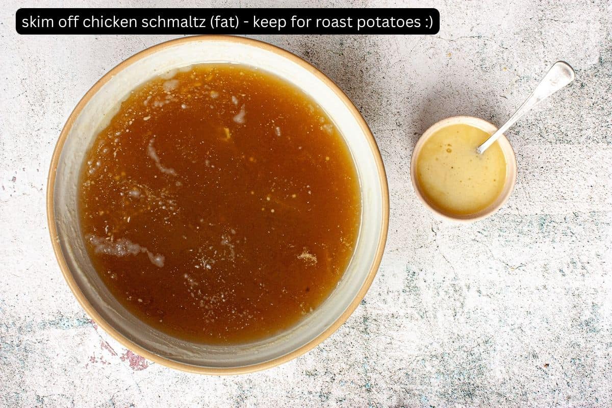 Large bowl of chicken broth with a small bowl of schmaltz (chicken fat) next to it.