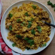 Bird's eye view of the finished pilau on a big white platter scattered with coriander leaves.