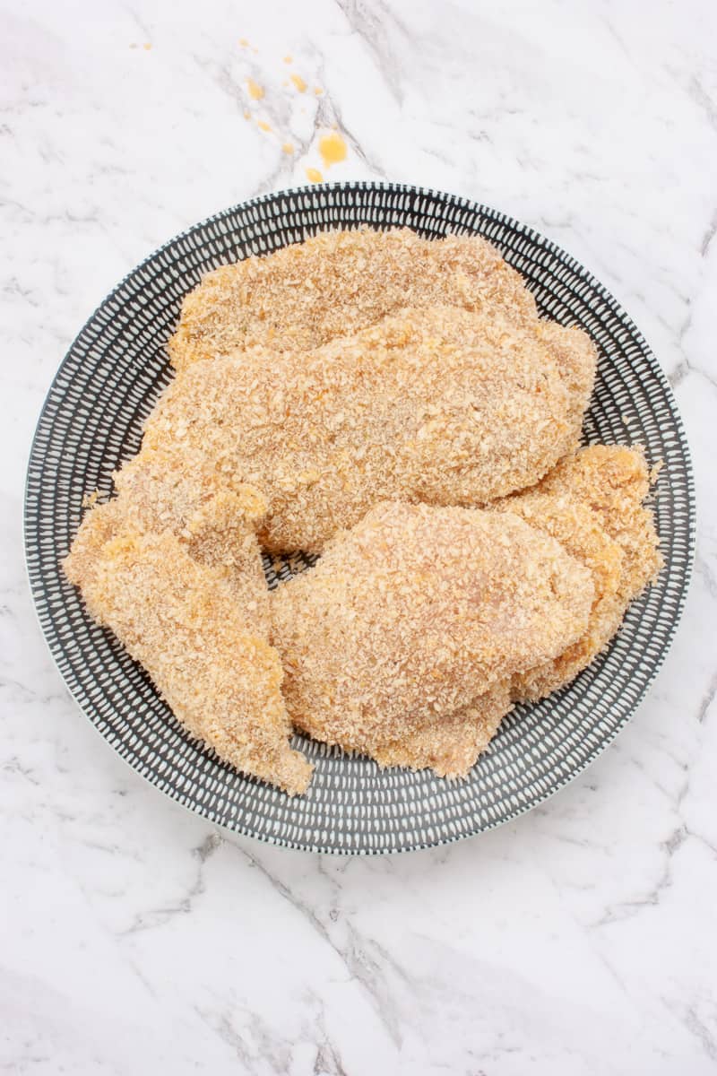 Pile of chicken schnitzel on a plate ready to cook.