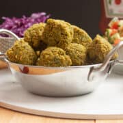 Fried falafel balls piled high in a metal bowl.