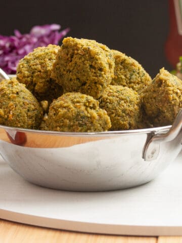 Fried falafel balls piled high in a metal bowl.