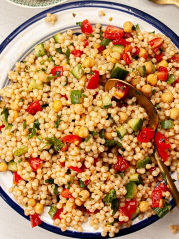 Colourful giant couscous salad in a large bowl.