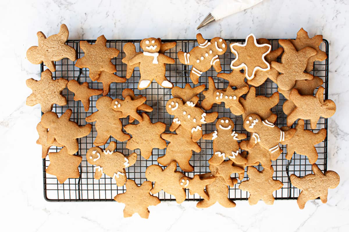 Cooked gingerbread biscuits on a cooling rack. Some are decorated with white icing.