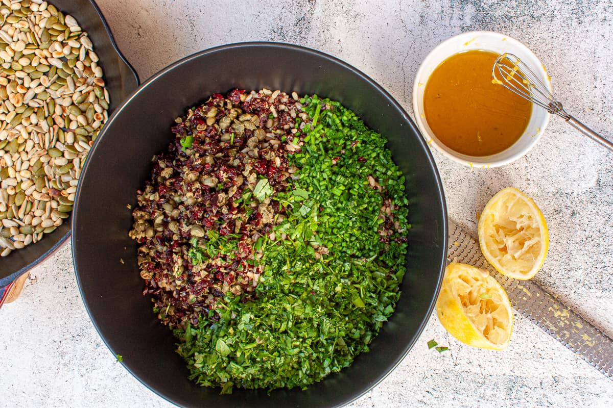 Ingredients for grain salad in a black bowl ready to be tossed together.