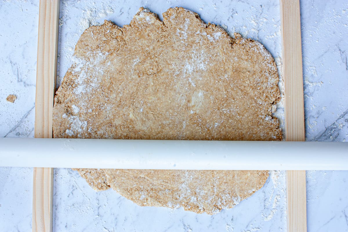 Pastry being rolled out between two strips of wood. 