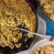 Top view of a wide pan filled with macaroni cheese being served family style.