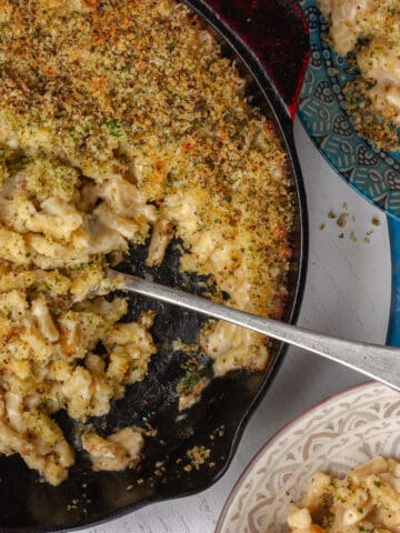 Top view of a wide pan filled with macaroni cheese being served family style.