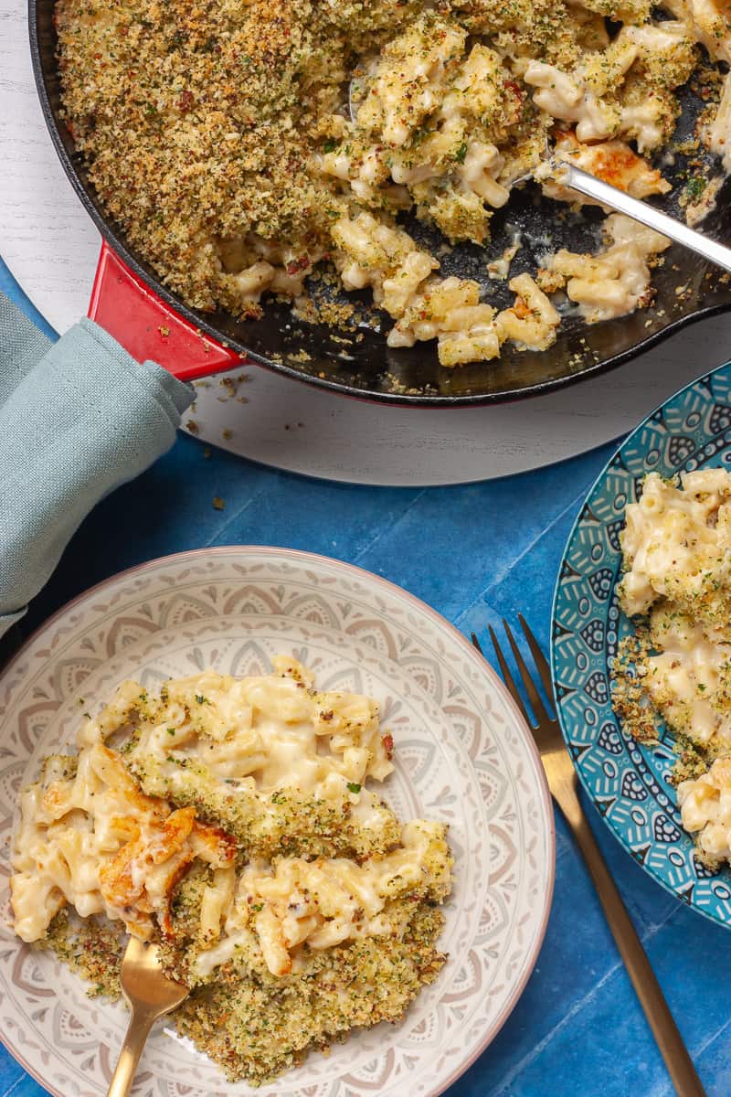 Top view of a wide pan filled with macaroni cheese being served family style.