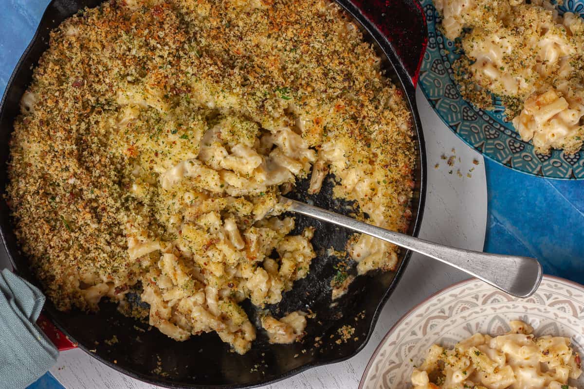 Top view of a wide pan filled with macaroni cheese being served family style.