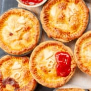 Top view of individual meat pies personalised with initial decorations and hearts.