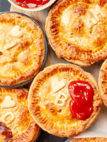 Top view of individual meat pies personalised with initial decorations and hearts.