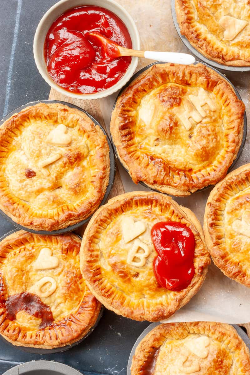 Top view of individual meat pies personalised with initial decorations and hearts.