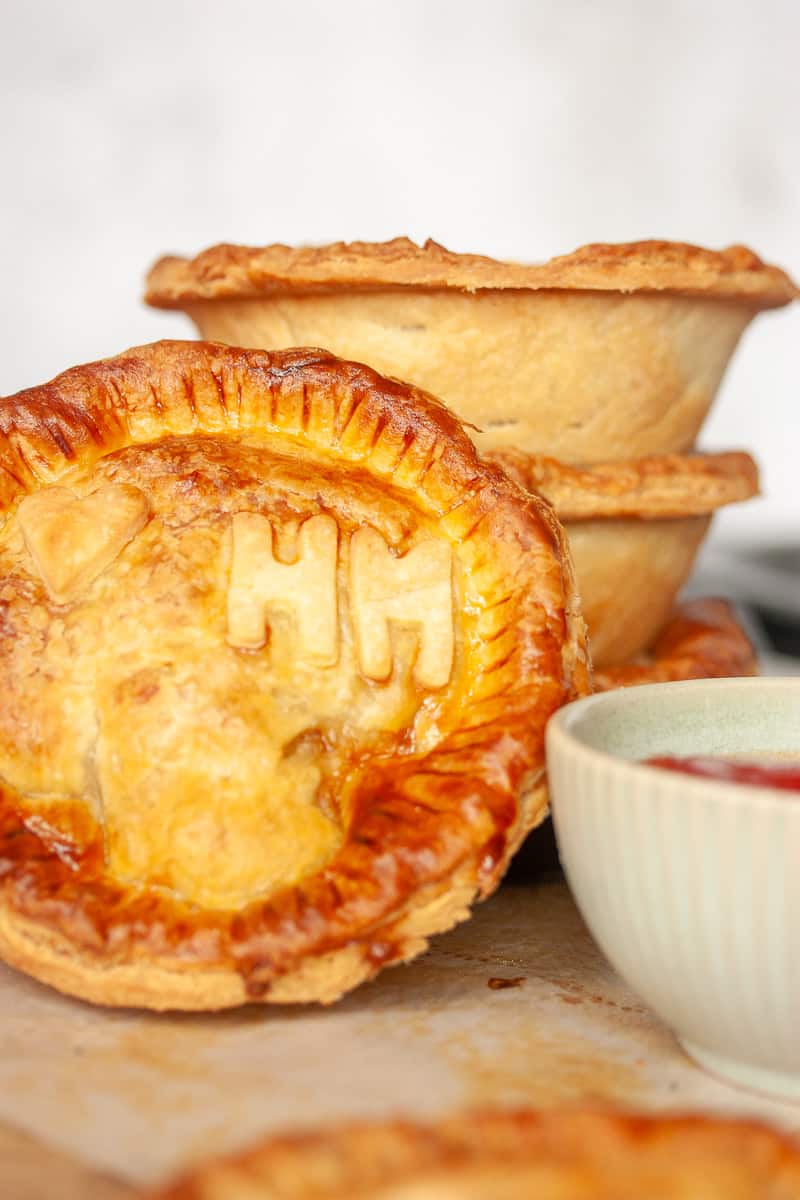 Stacked individual meat pies. One is on its side facing the camera.