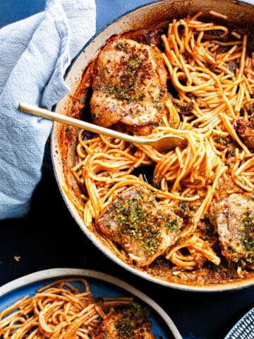 Tangle of spaghetti strands with chicken pieces served family-style.