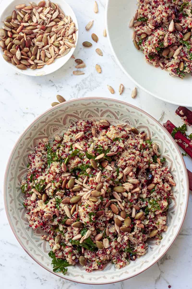 Top view of a generous portion of quinoa salad in a bowl, sprinkled with toasted seeds.