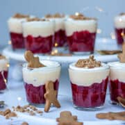 A group of rhubarb, custard and gingerbread trifles. Little gingerbread men in and around the glasses.