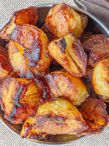 A pile of very crispy-looking roast potatoes in a silver bowl.