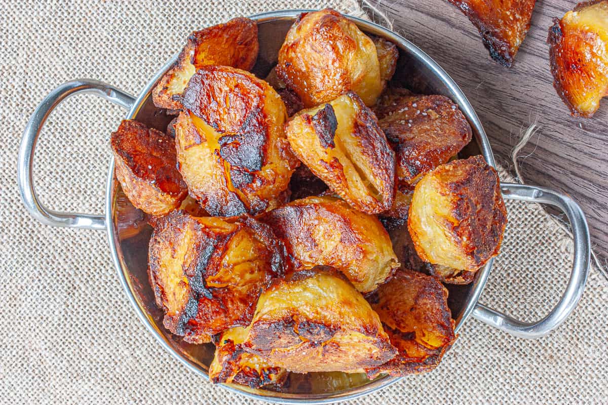 A pile of very crispy-looking roast potatoes in a silver bowl.