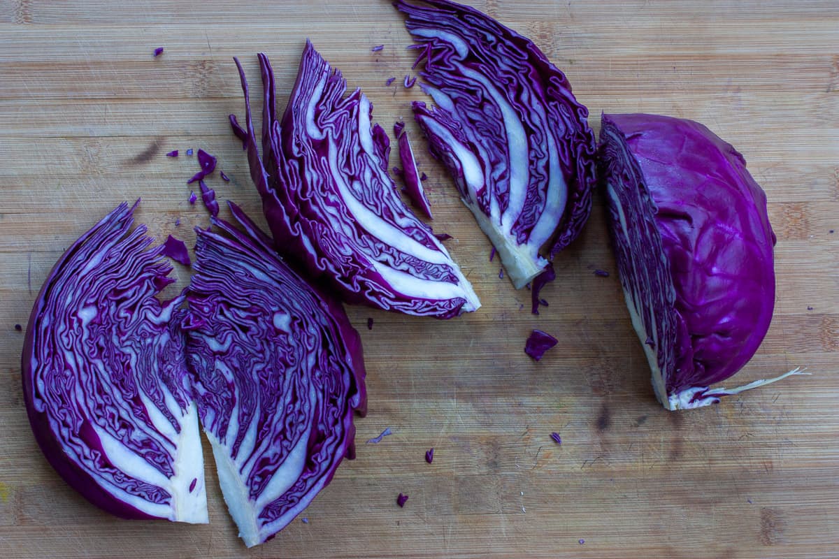 Purple cabbage wedges on a chopping board.