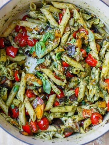 Looking down into a massive pot of completed pasta dish. Pops of red from the cherry tomatoes and red capsicum.