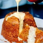 Custard being poured over a whole steamed pudding.