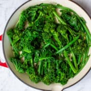 Glossy bright green veg in a large shallow red dish.