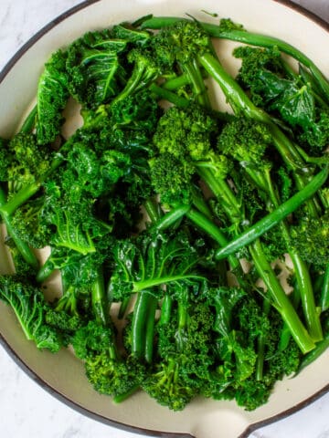 Glossy bright green veg in a large shallow red dish.