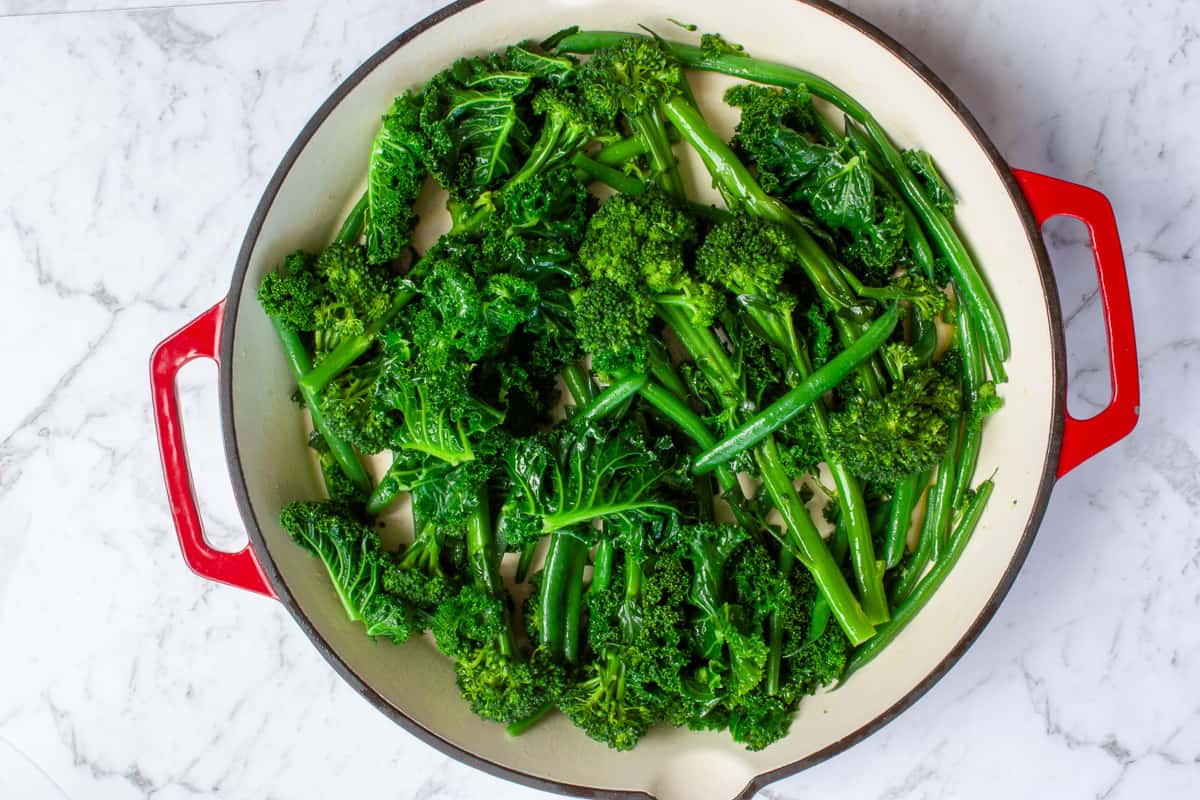 Glossy bright green veg in a large shallow red dish.