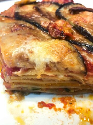 Close-up of a cross section a baked lasagna portion showing five layers of pasta and filling.